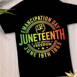 Peut inclure: Un t-shirt noir avec un motif circulaire représentant un poing levé. Le texte indique EMANCIPATION DAY, JUNETEENTH, BLACK AMERICAN FREEDOM et JUNE 19TH 1865. Les lettres présentent un dégradé de couleurs vert, jaune, orange et rouge.