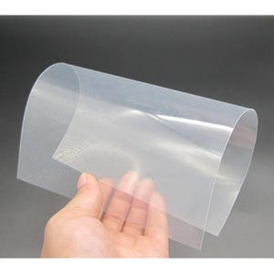Puede incluir: Una mano sosteniendo dos hojas de plástico transparente y claro. Las hojas están ligeramente curvadas y parecen delgadas y flexibles. El fondo es de color gris oscuro sólido.