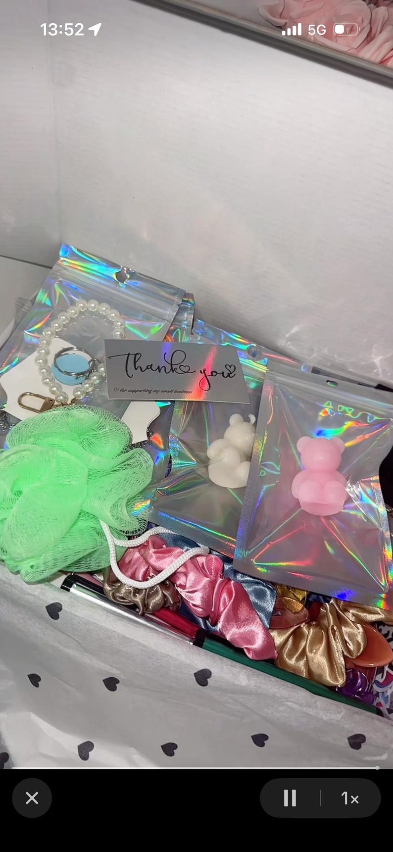 May include: A gift box filled with various items, including a pearl bracelet, a green loofah, scrunchies, and small bear-shaped soaps. A card with the words "Thank you" is also visible.