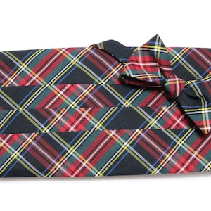 May include: A black and red plaid bow tie and cummerbund set. The bow tie is tied and the cummerbund is folded.