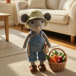 Puede incluir: Una muñeca de ratón de ganchillo con un sombrero de camuflaje y un peto azul, sosteniendo una pequeña cesta llena de zanahorias y rábanos. La muñeca tiene zapatos marrones y una pequeña herramienta de jardinería adjunta a su peto. La escena está ambientada en el interior sobre una alfombra color crema.