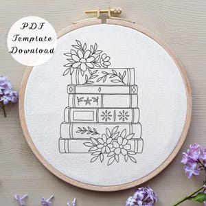 May include: A circular wooden embroidery hoop containing white fabric with a black line art pattern of a stack of five books decorated with floral motifs. The text PDF Template Download is printed in black on the upper left side of the image.