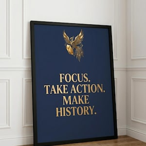 Puede incluir: Un estampado enmarcado con un fondo azul marino y texto dorado que dice "FOCUS. TAKE ACTION. MAKE HISTORY." Una ilustración de un fénix dorado está en la parte superior. El marco es negro.
