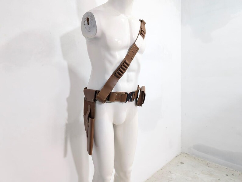 May include: A brown leather gun belt and shoulder holster set. The belt features a series of bullet loops and a buckle. The shoulder holster has a strap that goes over the shoulder and connects to the belt. The set includes a holster for a gun.