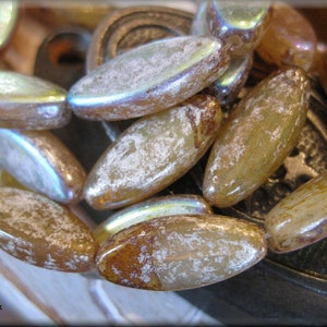 May include: A strand of iridescent glass beads in shades of brown and gold. The beads are oval shaped and have a textured surface.