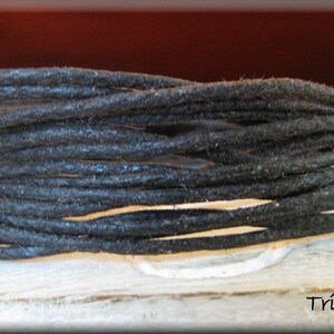 May include: A close-up of a spool of black waxed cord. The cord is wound tightly and is ready for use in crafting projects.