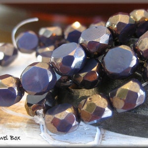 May include: A strand of dark purple faceted glass beads. The beads have a metallic sheen and are strung on a clear thread.