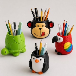 Op de afbeelding: Vier eigenzinnige pennenbakjes in de vorm van een schildpad, aap, papegaai en pinguïn. De groene schildpad, zwarte aap, rode papegaai en zwart-witte pinguïn bevatten elk pennen en potloden. Deze kleurrijke bureau-organizers voegen een speelse toets toe.