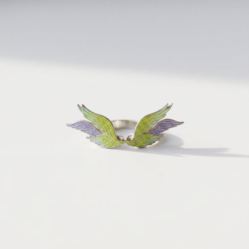 Close-up of angel wing enamel ring, showing the colorful enamel details and silver open band