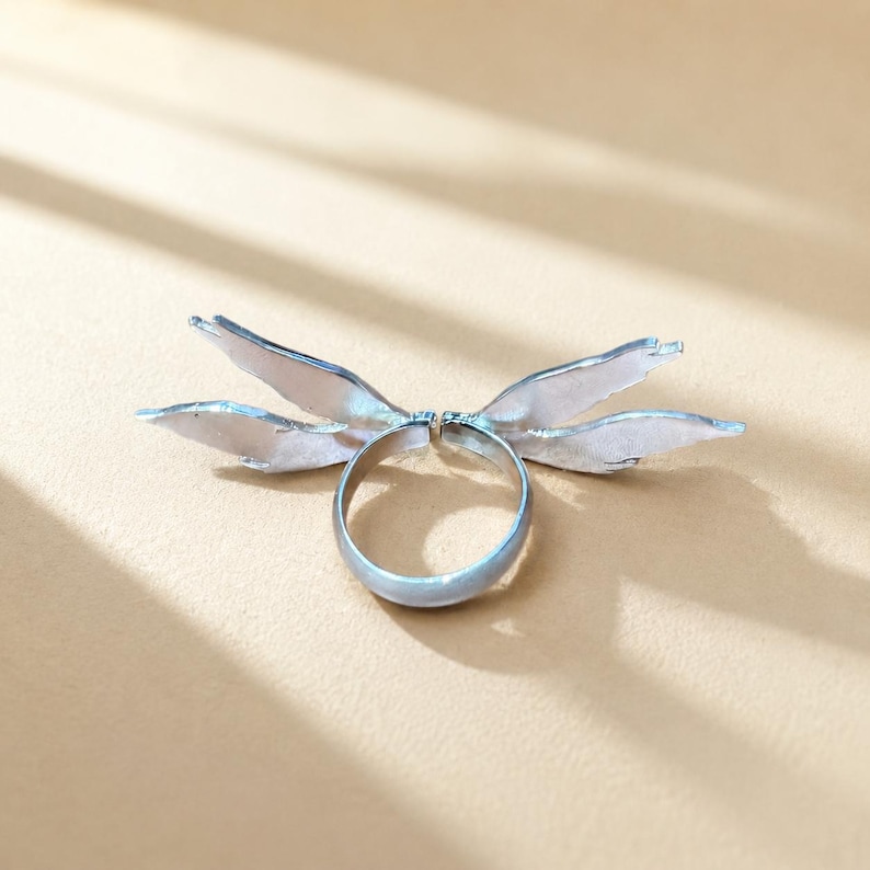 Silver angel wing enamel ring in natural light, showing the adjustable open design and wing details
