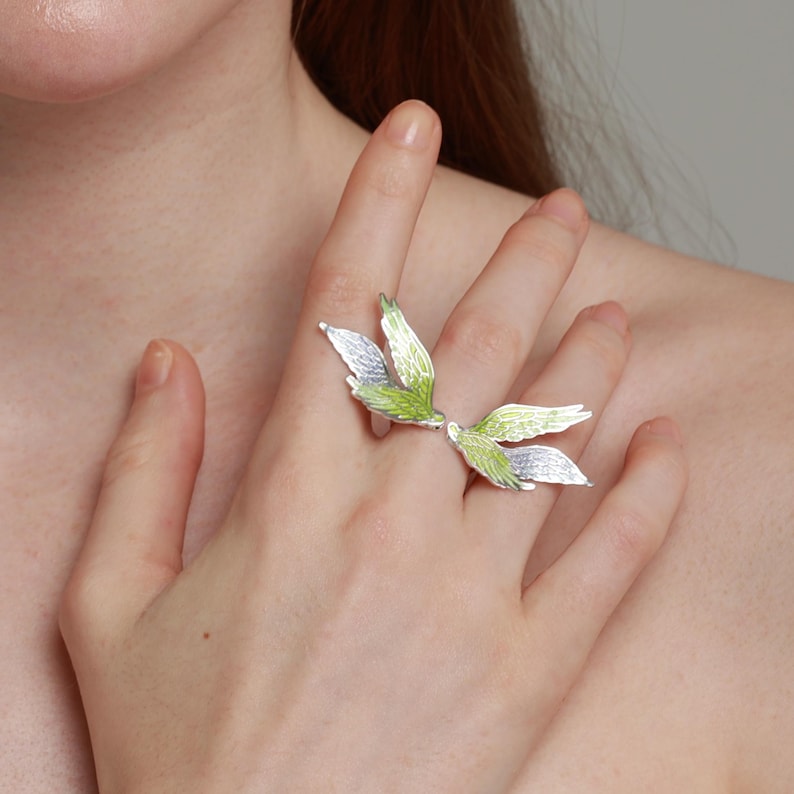 Pu&ograve; includere: Un anello argentato con un design a foglie. L'anello presenta pi&ugrave; foglie in tonalit&agrave; di verde e argento, creando un accessorio ispirato alla natura. Le foglie sono disposte in modo da sembrare che crescano dal dito.