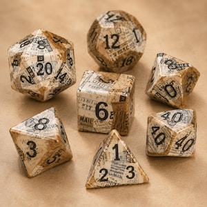 May include: A set of seven polyhedral dice featuring a vintage newspaper print pattern with black ink text and numbers. The collection includes a twenty-sided die, a twelve-sided die, a ten-sided die, an eight-sided die, a six-sided die, and a four-sided die.