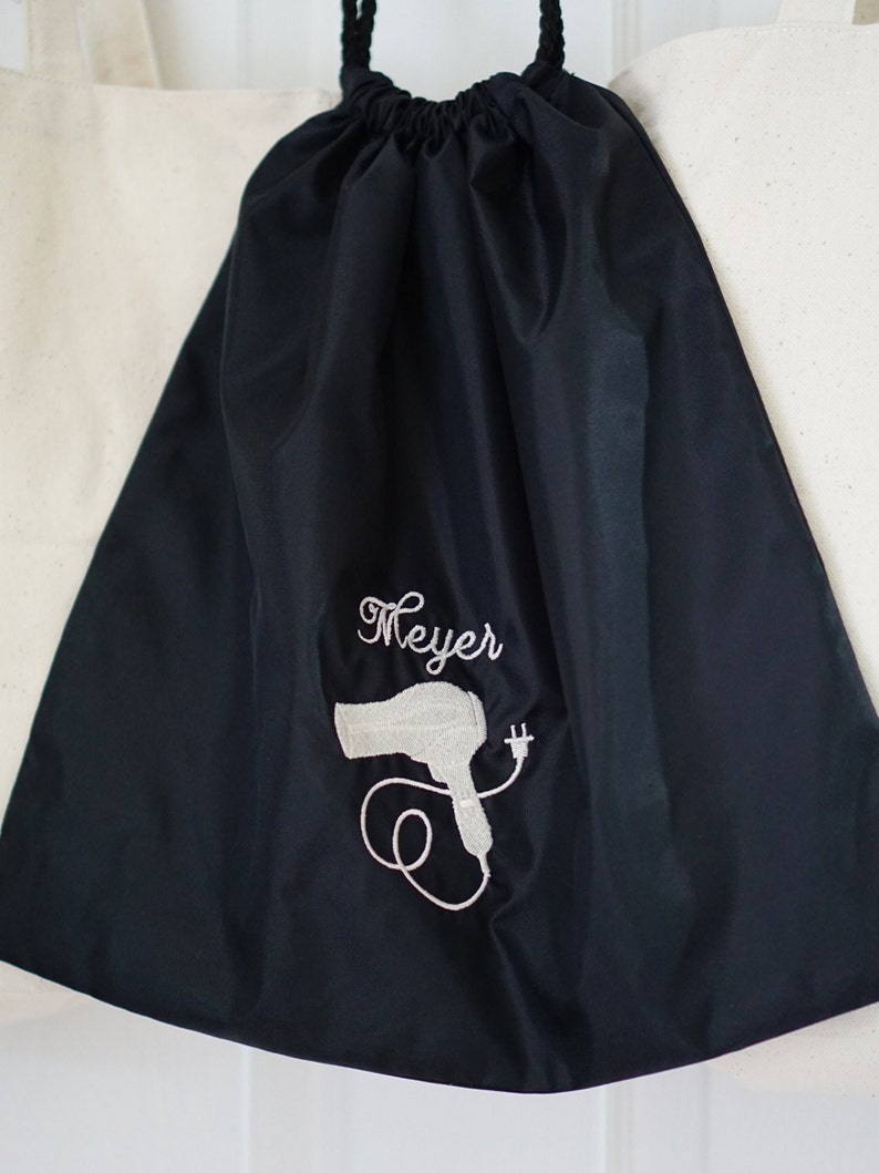 May include: Black drawstring bag with a white embroidered hairdryer and the name "Meyer" on the front.