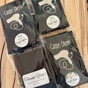 May include: Four black fabric pouches with white embroidery. Each pouch features a hairdryer design and the text "Carpe Diem". Each pouch has a round white sticker with the text "Thank You! Unful Stitches" and a small floral design.