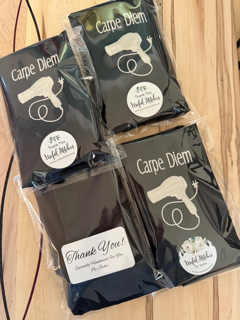 May include: Four black fabric pouches with white embroidery. Each pouch features a hairdryer design and the text "Carpe Diem". Each pouch has a round white sticker with the text "Thank You! Unful Stitches" and a small floral design.