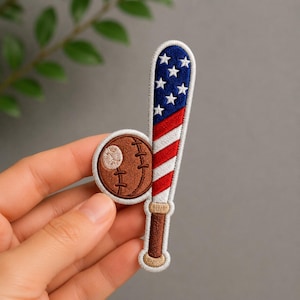 May include: Embroidered patch featuring a baseball and bat. The bat is decorated with the American flag design, with red and white stripes and blue stars. The baseball is brown with white stitching.