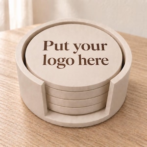 May include: A stack of five circular, light beige coasters housed in a matching cylindrical holder. The top coaster features the dark brown text "Put your logo here" printed in a serif font. The set has a smooth, matte finish throughout.