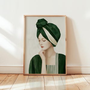 Peut inclure: Impression d'art encadrée représentant une femme aux yeux fermés, coiffée d'un turban vert foncé avec une bande blanche et d'un haut vert assorti. L'œuvre d'art est réalisée dans un style aquarelle doux, mettant en valeur le visage de la femme et le drapé élégant du tissu.