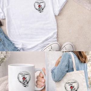 Op de afbeelding: Wit T-shirt, mok en draagtas met een afbeelding van een verkeerslicht met de tekst "PEOPLE ALWAYS LEAVE". Het verkeerslicht heeft een rood licht. De draagtas wordt door een persoon gedragen.