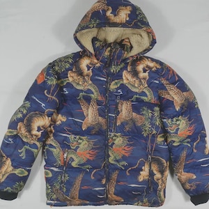 May include: A navy blue puffer jacket with a hood and a full-zip closure. The jacket features a repeating pattern of tigers, dragons, and tropical foliage. The hood is lined with a tan, fuzzy material.