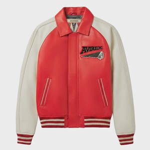 May include: Red and cream-colored leather jacket with the word "AVIREX" and a Native American head patch. The jacket has a collared neckline, cream-colored sleeves, and a striped hem and cuffs.