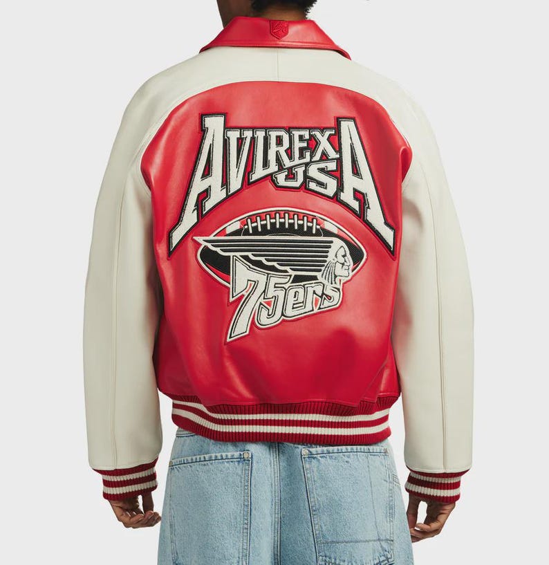 May include: A red and cream-colored letterman jacket with the text "AVIREX USA" and a football graphic on the back. The jacket has a ribbed hem and cuffs with red and white stripes. The jacket also has the text "75ers".