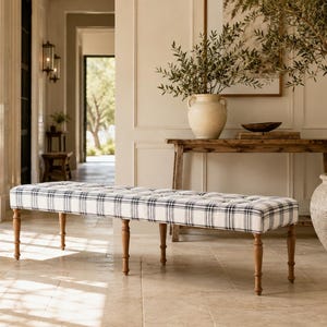 Peut inclure: Un banc rectangulaire capitonné doté d'un revêtement en tissu blanc à motif écossais noir. Le banc repose sur six pieds en bois tourné et effilé, d'une teinte brun moyen, offrant une base stable à l'assise allongée et rembourrée.