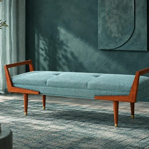 Puede incluir: Un banco rectangular con un asiento de tela azul claro capitoné, apoyado sobre una estructura de madera con reposabrazos angulados y cuatro patas cónicas con remates de metal dorado en la base, ofreciendo una superficie de asiento estructurada.