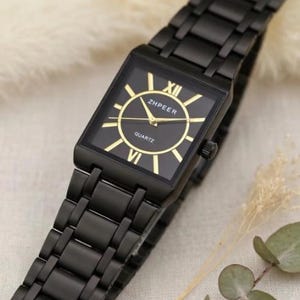 May include: A black wristwatch with a rectangular face and a matching black metal strap. The watch face is black with gold hands and Roman numerals. The brand name "ZHEER" is visible. The watch is a quartz movement.