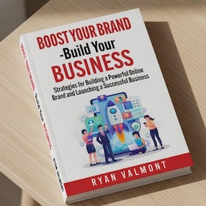 May include: A hardcover book titled "BOOST YOUR BRAND - Build Your BUSINESS" with a red and white cover. The cover features a graphic of a rocket ship launching from a digital screen, with illustrations of people. The author's name, Ryan Valmont, is at the bottom.