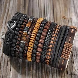 May include: A multi-strand bracelet set featuring a black leather band with an infinity symbol, various black and brown wooden beads, textured lava stone beads, braided leather cords, and a brown leather strap with horizontal stitching details.