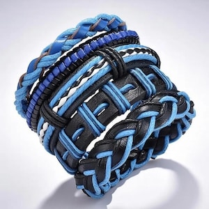May include: A multi-layered bracelet set featuring a combination of braided light blue cord, black leather-like straps, and blue and black woven elements. The design incorporates various textures including smooth bands and intricate braided patterns.