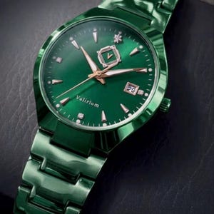 May include: A green wristwatch with a matching band. The watch face is green with gold-colored hands and markers. The date is displayed at the 3 o'clock position. The watch has the word "Valirium" on the face.