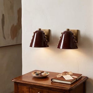 Puede incluir: Una taza de cerámica blanca con un asa negra y el texto "But First, Coffee" en negrita negra. La taza se encuentra sobre un fondo neutro, resaltando su diseño sencillo.