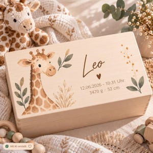 Könnte beinhalten: Eine rechteckige Erinnerungsbox aus hellem Holz mit einem Aufdruck einer Giraffe, grünen Blättern und Weizenähren. Der Text lautet Leo, 12.06.2026 - 10:31 Uhr, 3470 g - 52 cm, ergänzt durch ein kleines Herzsymbol.