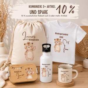 May include: A set featuring a beige drawstring bag, a white t-shirt, a white water bottle, and a wooden lunch box, all decorated with a brown bear illustration and personalized text. The text includes "Lauras Krimskrams", "Kindergartenkind 2026", and "Emilia".