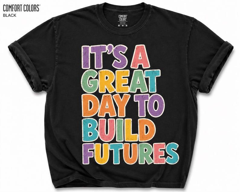 May include: Black Comfort Colors t-shirt with the text "IT'S A GREAT DAY TO BUILD FUTURES" in colorful, outlined letters. The shirt has a crew neck and short sleeves, perfect for casual wear.