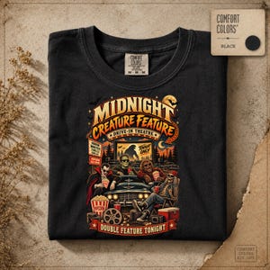 Può includere: Una t-shirt nera con una stampa grafica intitolata Midnight Creature Feature Drive-In Theatre. Il design mostra un'auto classica con un vampiro, il mostro di Frankenstein, un lupo mannaro e uno scheletro che guardano un film con dei popcorn.