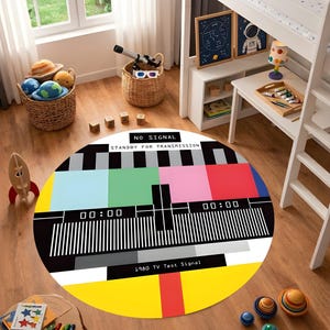 May include: A round rug with a colorful 1980 TV test signal design. The rug features a black and white bar pattern, with blocks of green, pink, red, and yellow. The text "NO SIGNAL STANDBY FOR TRANSMISSION" is displayed. The rug is in a child's room.