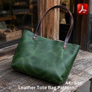 Könnte beinhalten: Eine grüne Ledertasche mit braunen Henkeln. Die Tasche hat eine rechteckige Form und besteht aus strukturiertem Leder. Die Henkel sind mit goldfarbenen Nieten befestigt. Der Text "Leather Tote Bag Pattern" und "A4 - Size" sind sichtbar.