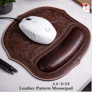 Op de afbeelding: Bruin leren muismat met bloemmotief en ingebouwde polssteun. Een witte computermuis ligt erop. De tekst "A4-SIZE Leather Pattern Mousepad" staat onderaan.