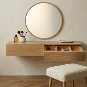 May include: A white ceramic mug with a black handle and the text "But First, Coffee" in a bold, black font. The mug is set against a blurred background, suggesting a cozy setting.