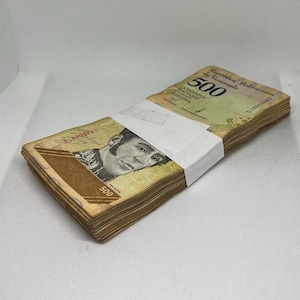 May include: A bundle of Venezuelan 500 Bolivar banknotes, secured with a white paper band. The notes display a portrait and Spanish text. The bills are in shades of green, brown, and tan.