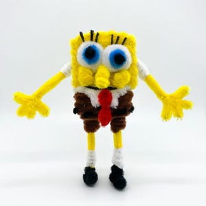 May include: A white ceramic mug with a black handle and the text "But First, Coffee" in a black, bold font. The mug is on a white surface. The mug is approximately 10 cm tall.