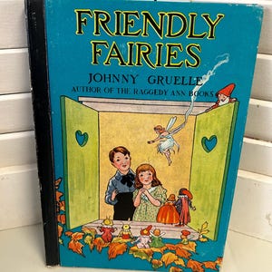 May include: A vintage children's book titled "Friendly Fairies" by Johnny Gruelle, author of the Raggedy Ann books. The cover features a blue background with a yellow and green window frame, a fairy flying, and a group of children and fairies.
