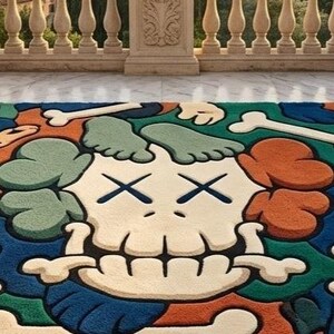 May include: A colorful rug featuring a cartoon skull design with crossed-out eyes and bone accents. The rug incorporates shades of blue, orange, green, and cream. The rug is placed on a marble surface with a scenic background.