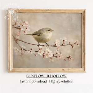 Puede incluir: Impresión enmarcada que representa un pequeño pájaro posado en una rama florecida. El pájaro tiene plumas de color marrón claro y gris, y las flores son blancas y rosas. El marco es de color marrón claro. El texto "SUNFLOWER HOLLOW" está en la parte inferior.