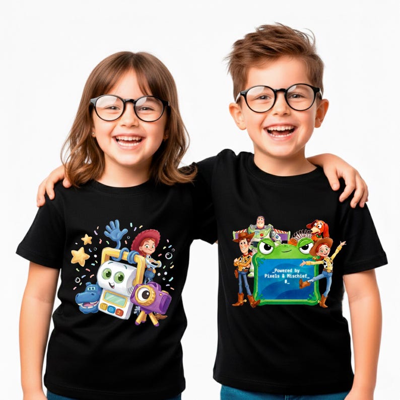 Pu&ograve; includere: Due bambini con magliette nere con grafiche colorate di Toy Story. Una maglietta presenta Jessie, una fotocamera e altri personaggi. L'altra maglietta ha Buzz Lightyear, Woody e il testo "Powered by Pixels & Mischief."