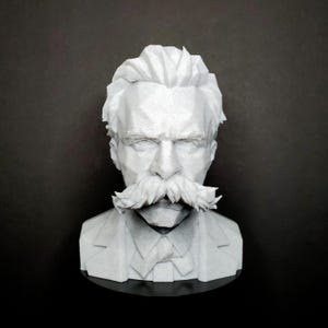Puede incluir: Un busto geométrico blanco de estilo low-poly que representa a una persona con un bigote grueso y prominente, cabello peinado y una camisa con cuello y corbata. La escultura presenta facetas angulares y afiladas en la cabeza y la ropa.