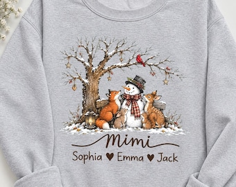 May include: A light gray crewneck sweatshirt featuring a graphic print of a snowman, a fox, a deer, and two rabbits under a tree. The text reads Mimi, Sophia, Emma, and Jack, separated by heart symbols. The design includes a lantern and ornaments.